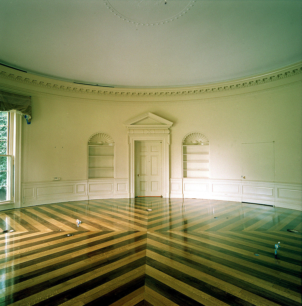 The Oval Office without any furniture or books, just the empty built-in bookcases and the wood floor with a zigzag pattern