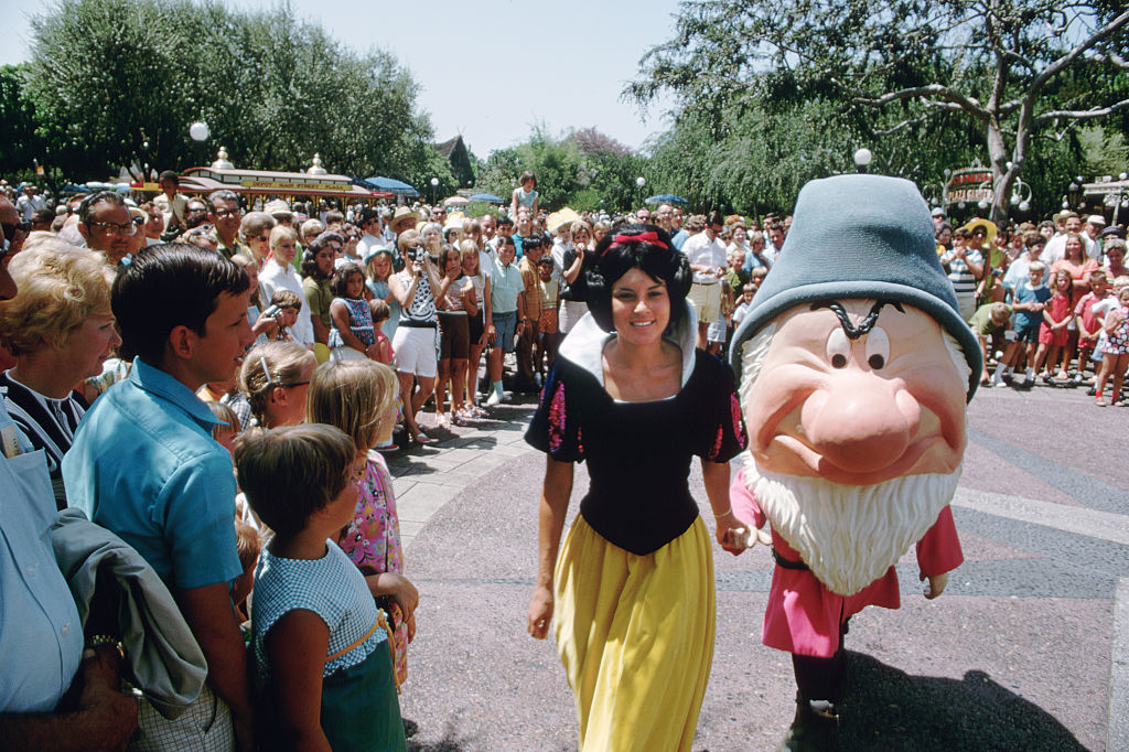 Snow White and Grumpy characters at Disneyland are walking through the park