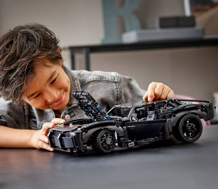 child playing with Batmobile Lego toy