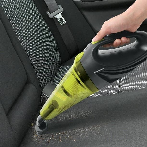 A portable vacuum cleans a car seat