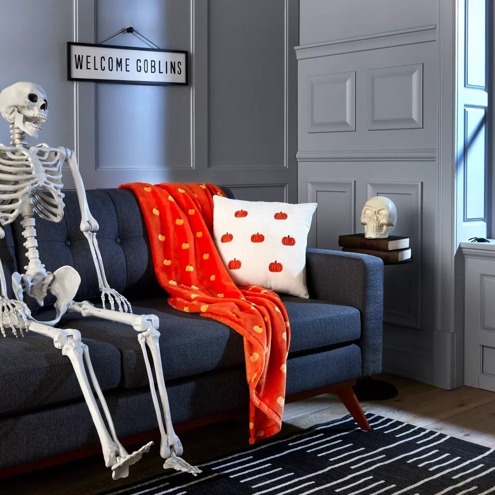the orange blanket on a couch next to a skeleton