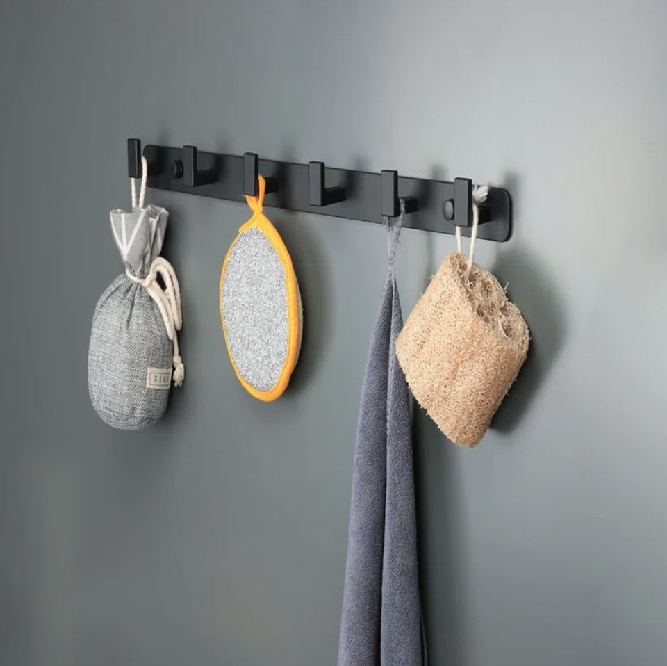 black metal wall hanging with hooks holding towels and sponges