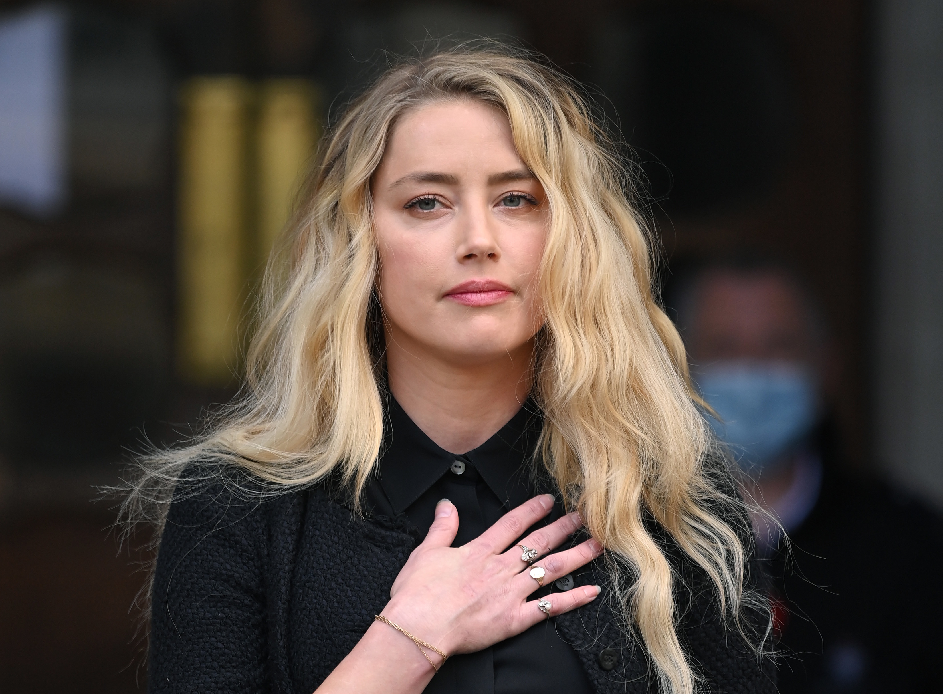 Amber Heard with her hand over her heart
