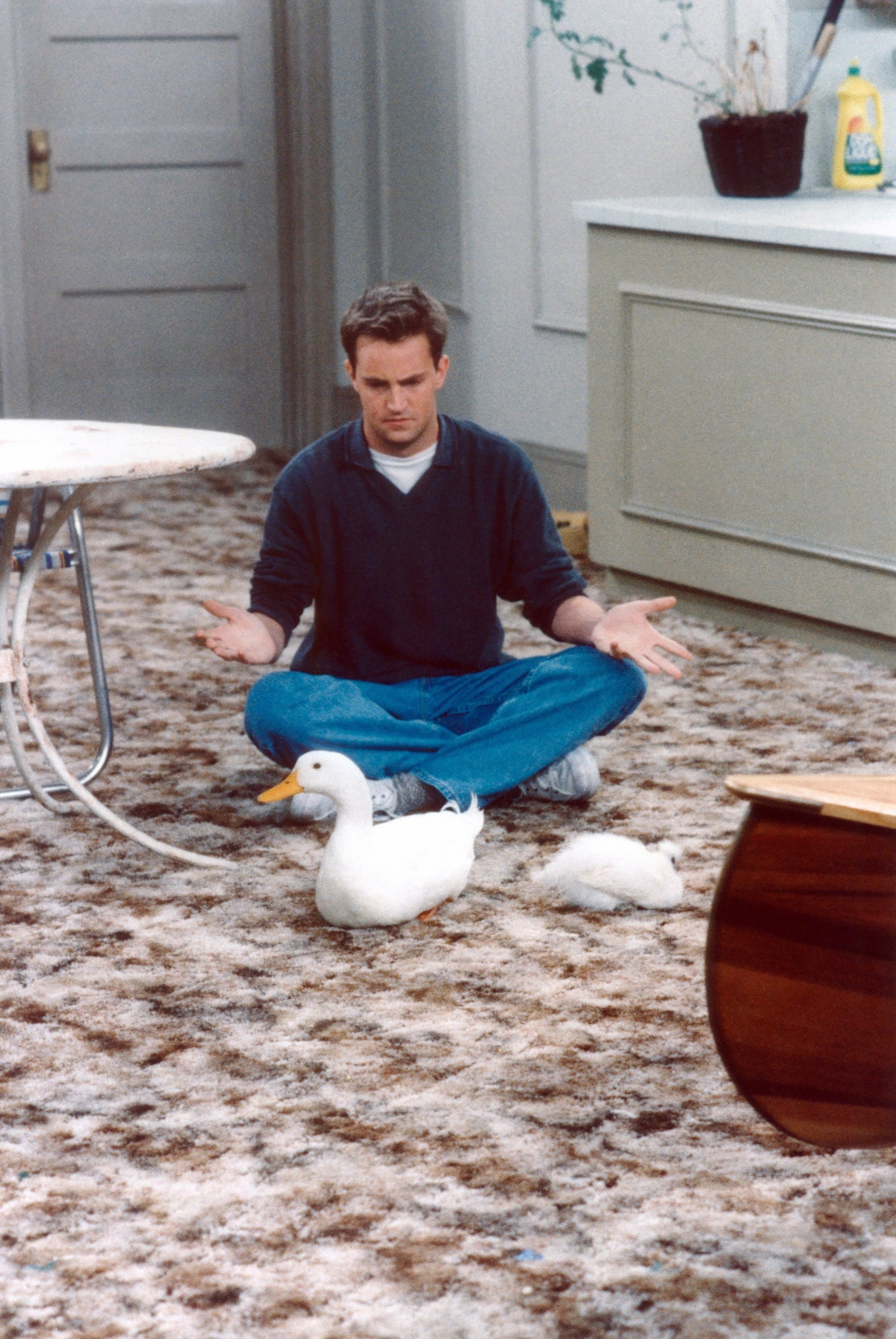 Matthew sitting on the floor with a duck in a scene from &quot;Friends&quot;