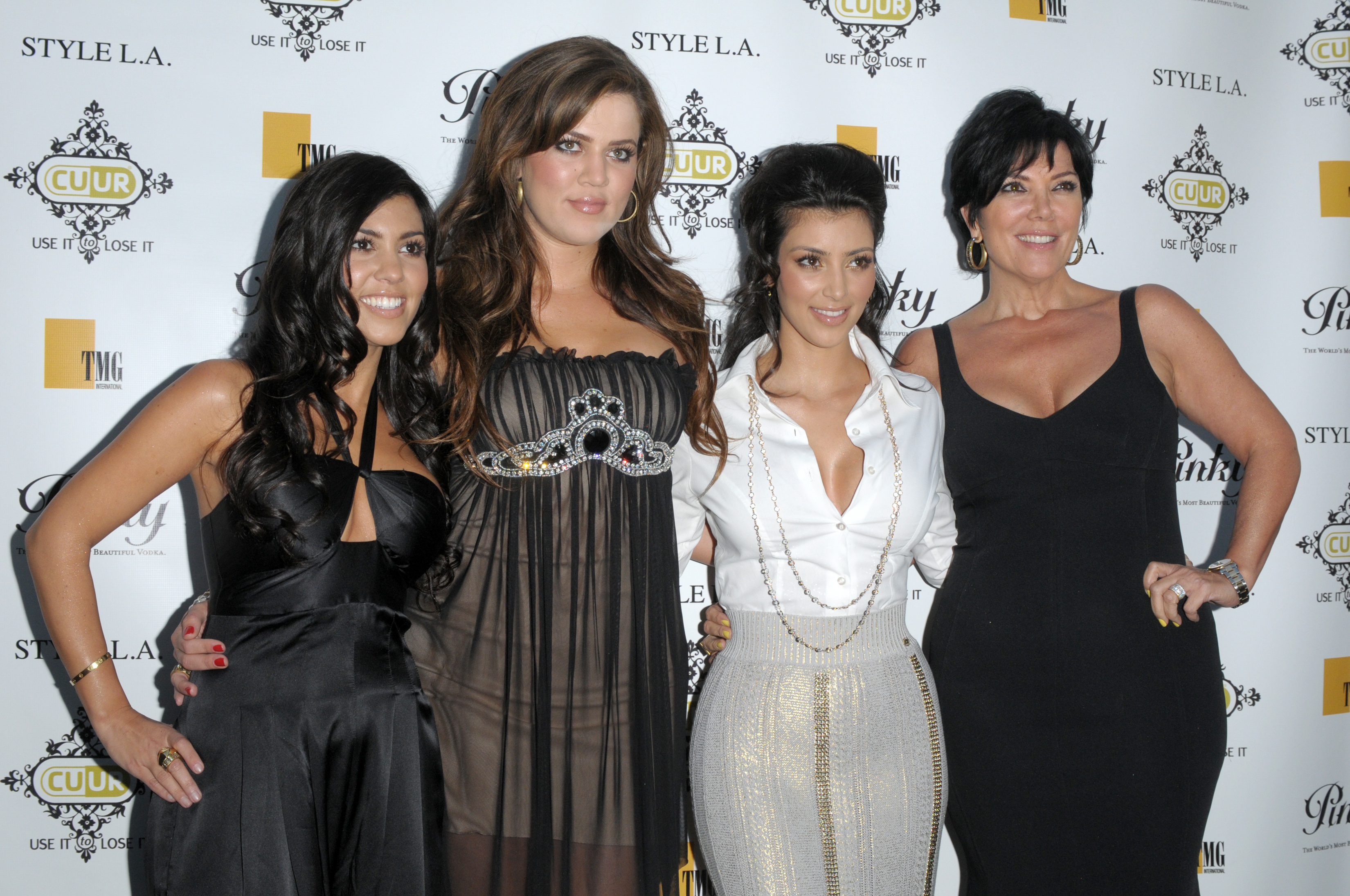 Khloé, Kourtney, and Kim Kardashian with Kris smiling at a media event