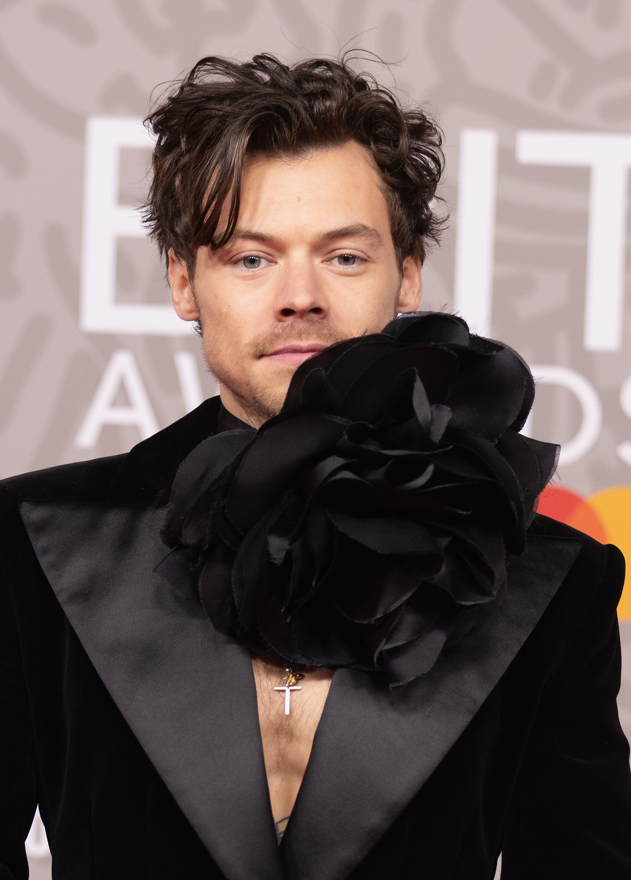 Closeup of Harry Styles in a suit with a large flower detail on the neck