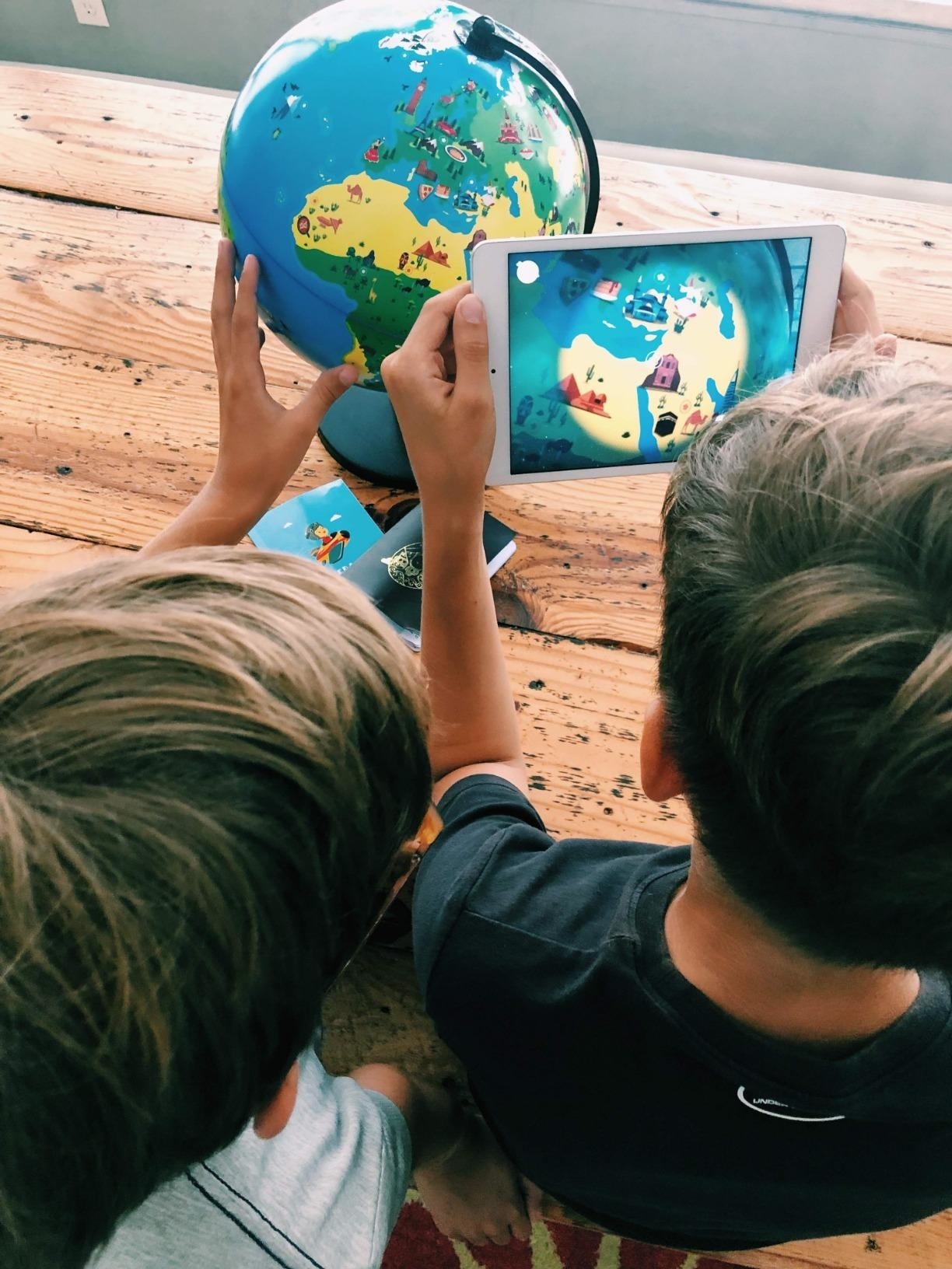 Two children using a tablet with the globe