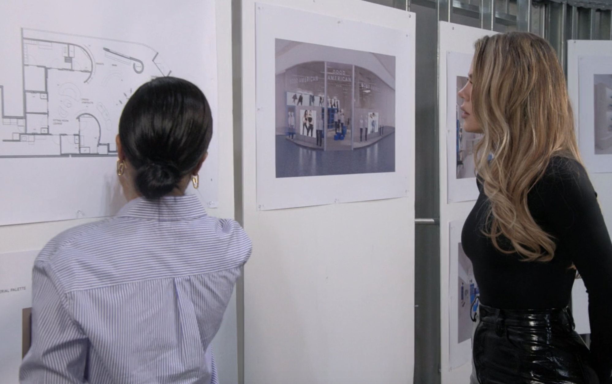 Emma and Khloé at a wall looking at plans