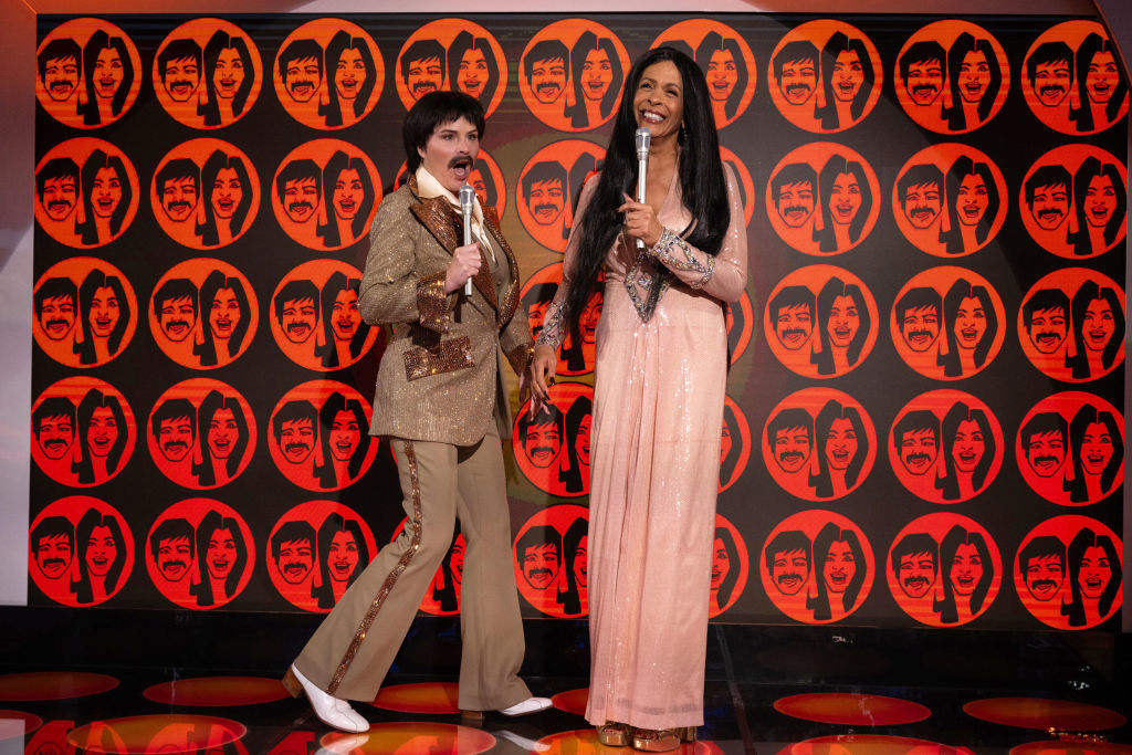 both in wigs and holding mics on stage