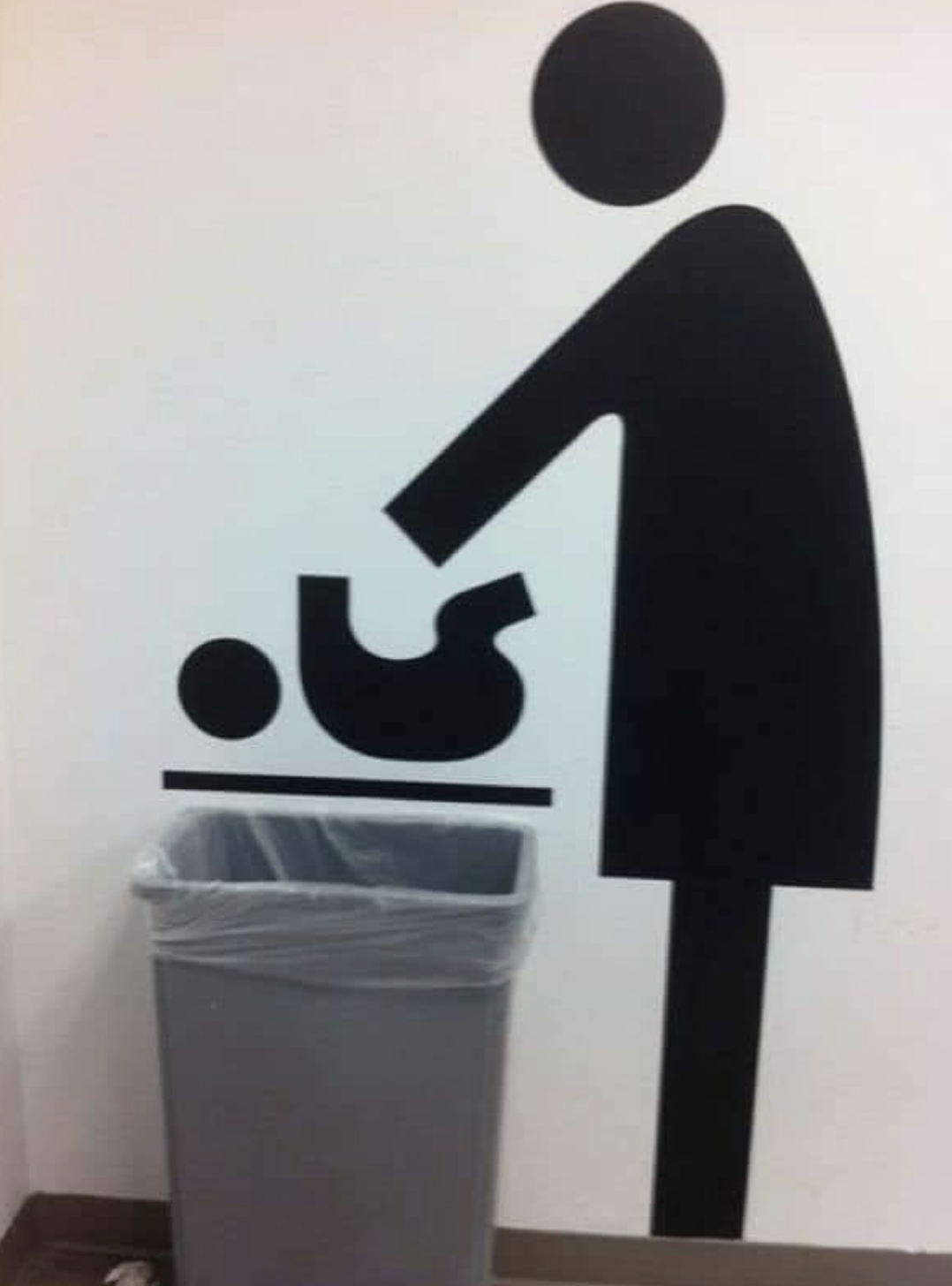 trash can under wall decal that looks like a baby is being thrown inside the can