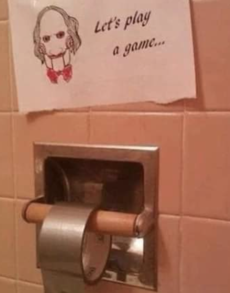 sign reads, let&#x27;s play a game above a toilet paper dispenser that has duct tape instead