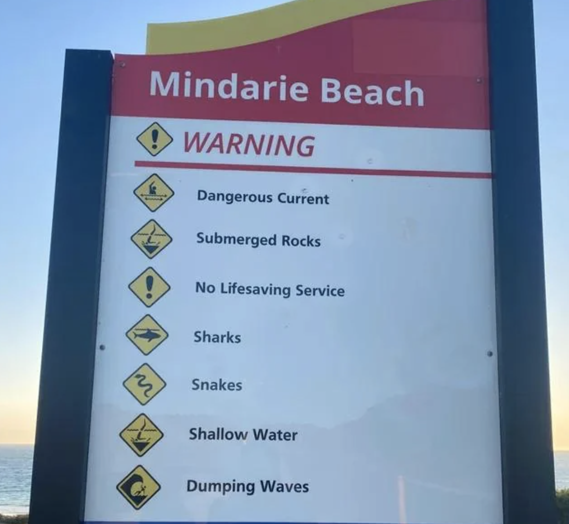sign at the beach has an icon that looks like a shark with helicopter wings