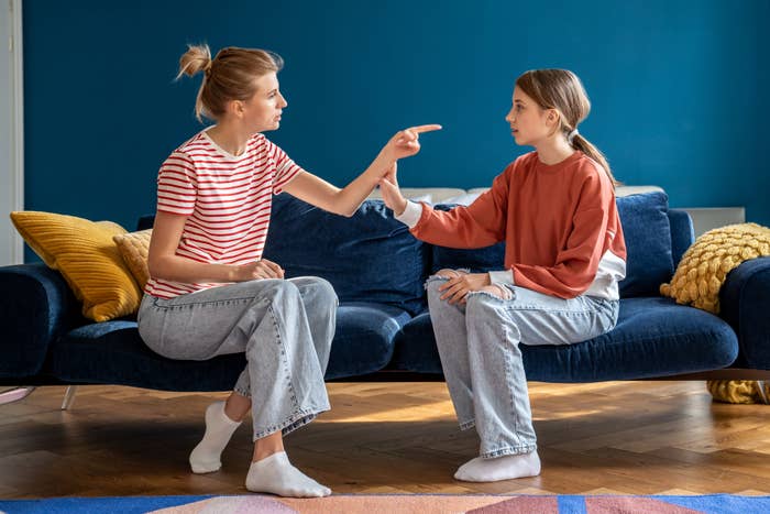 mom and adolescent kid having conflict sitting together on sofa in living room at home