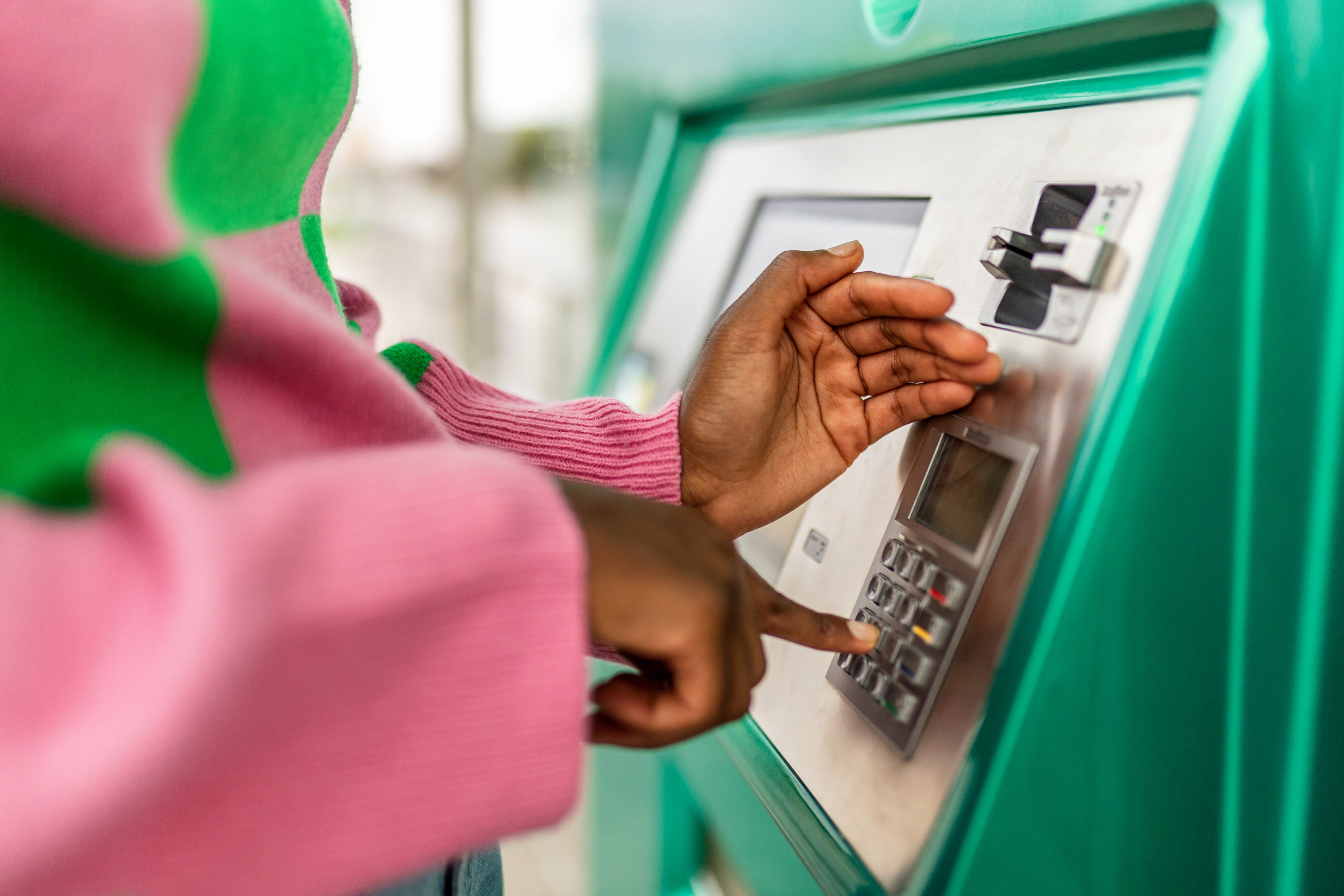 a woman punches her PIN into an ATM