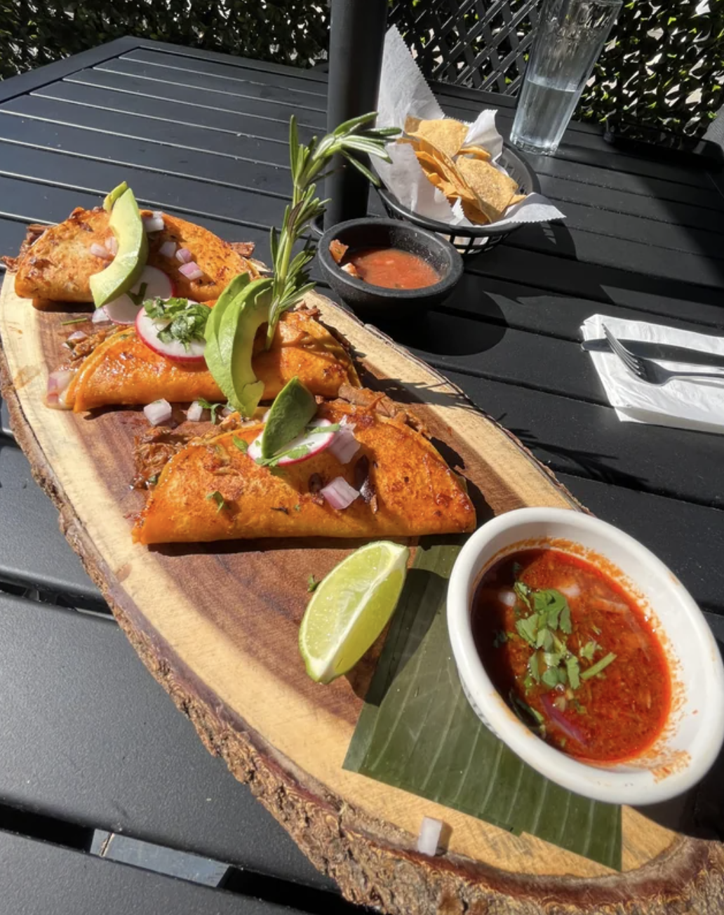 Birria tacos are served on a huge slab of wood
