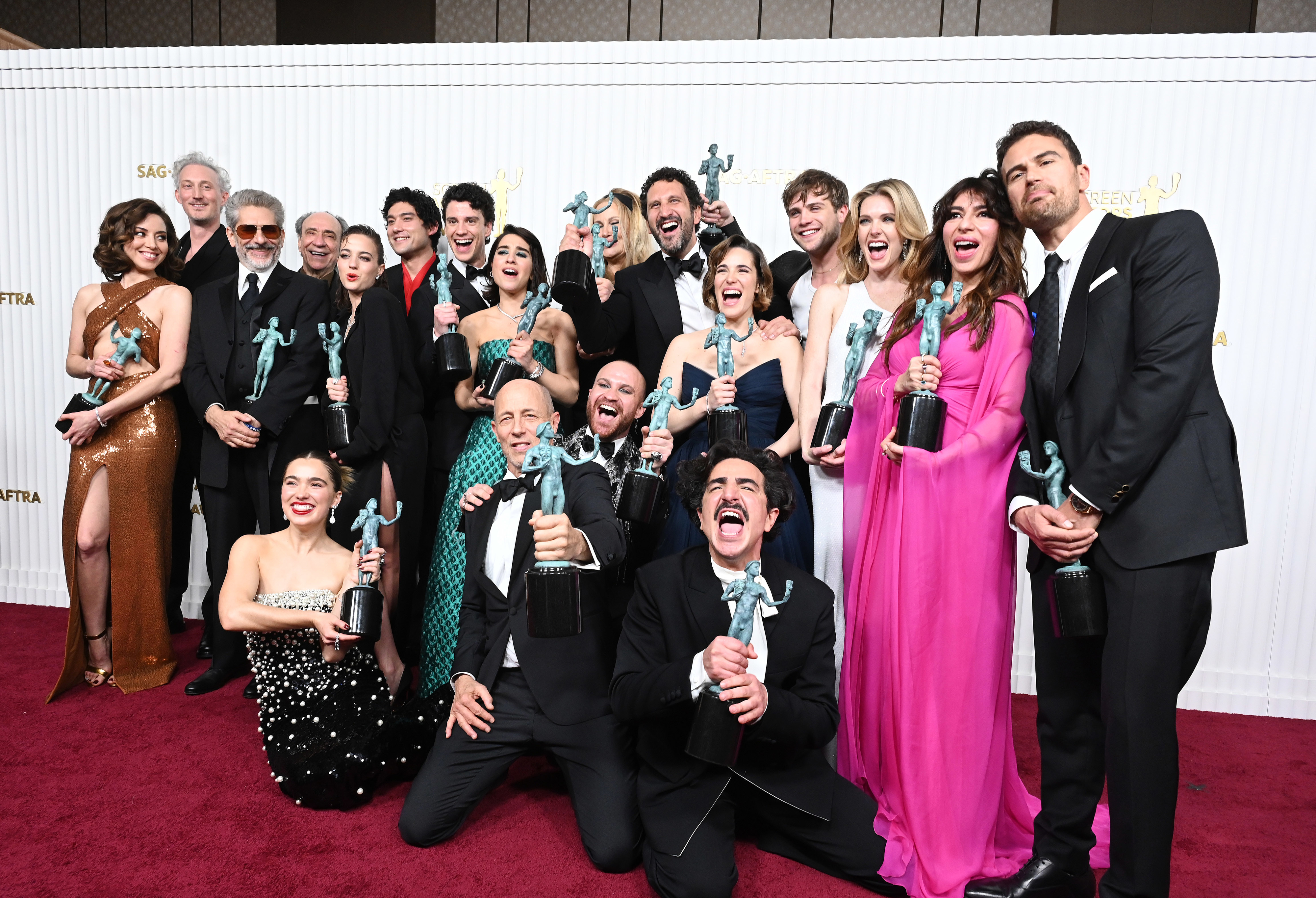 The cast and crew on the red carpet holding awards
