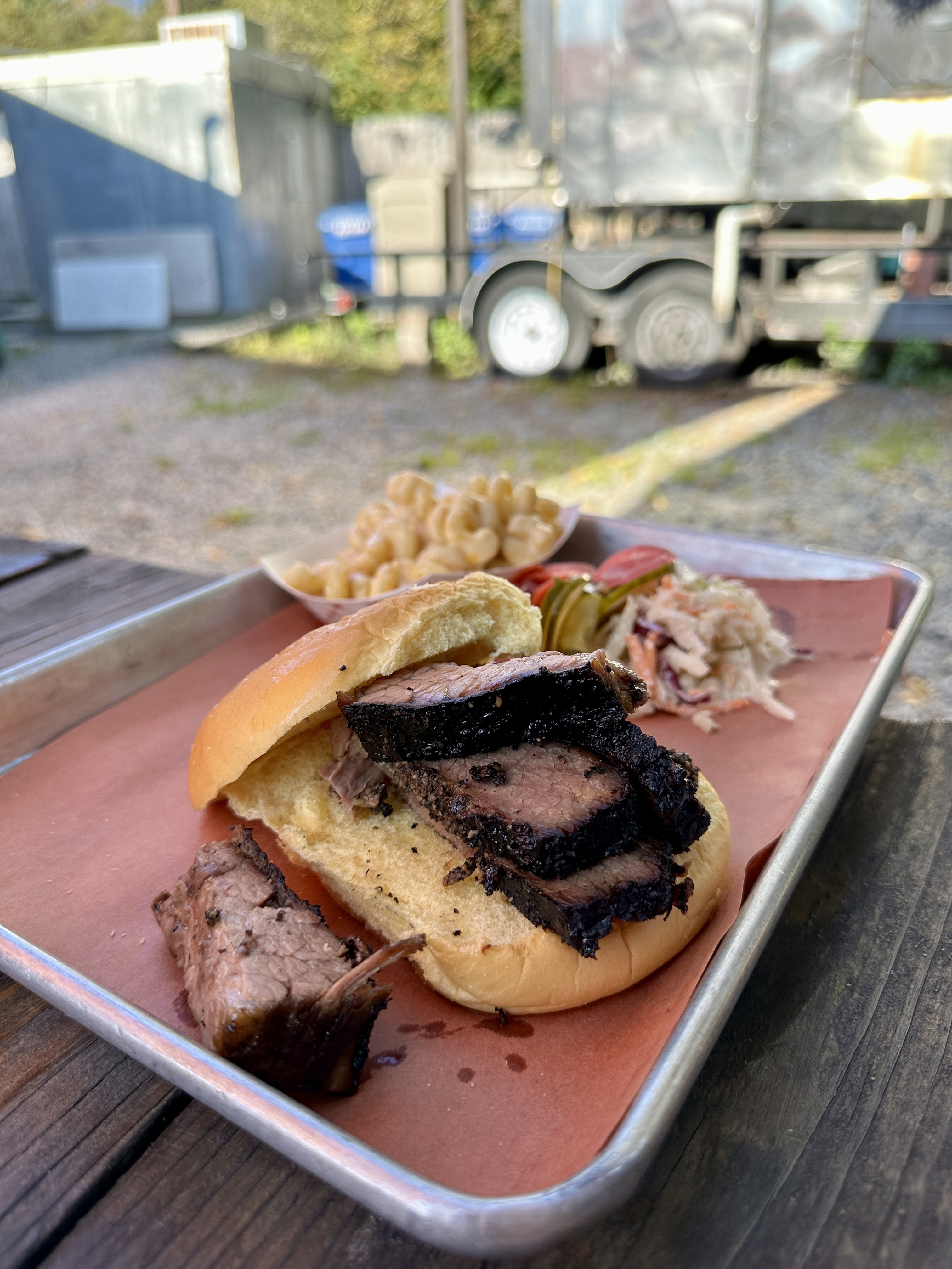 plate of food at BBQ restaurant with smoker in trailer behind it
