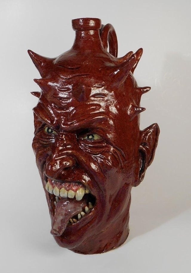 vase is of a realistic satanic head with large teeth and tongue coming out