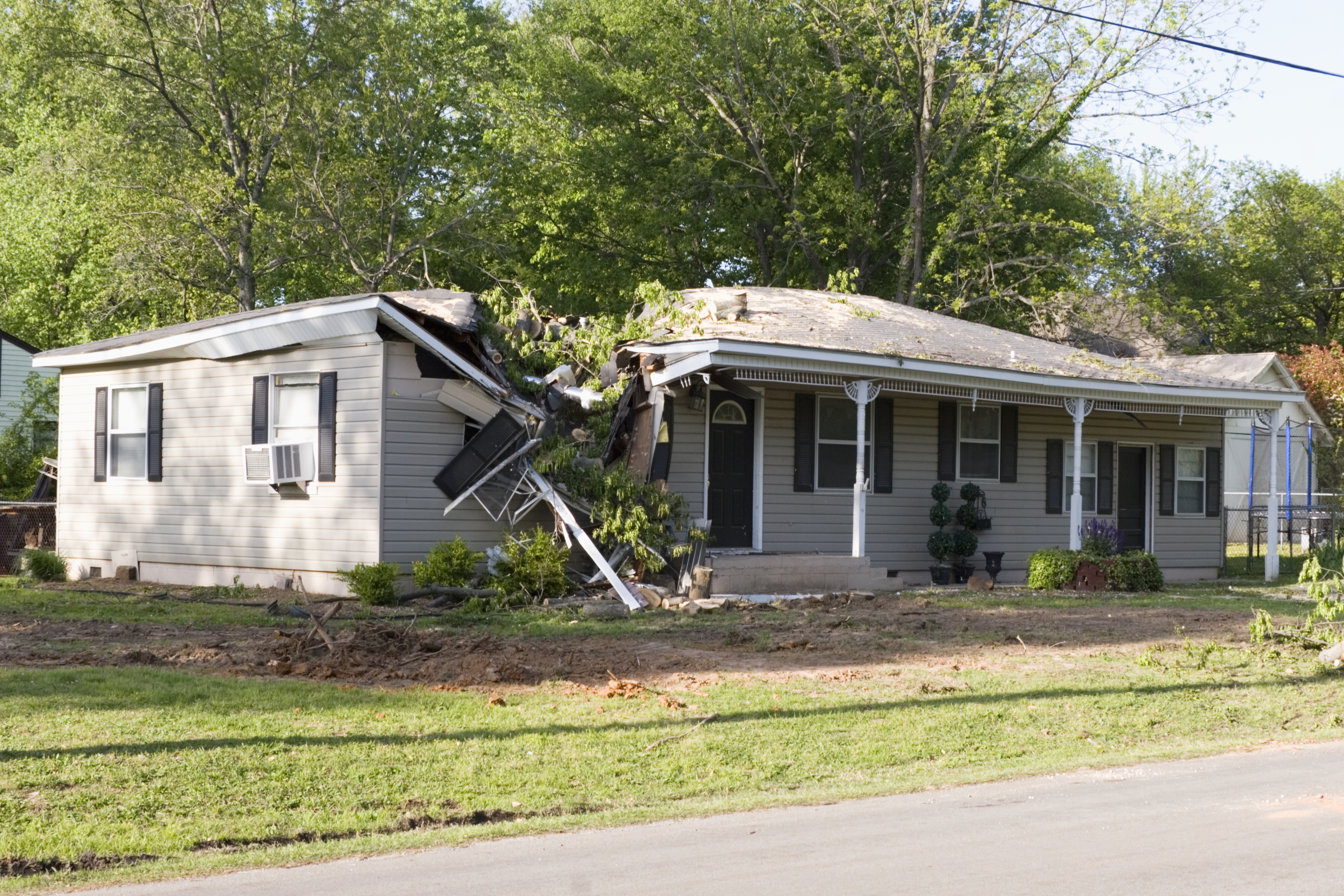 Storm damage on a home, involving a tree that crashed through a roof