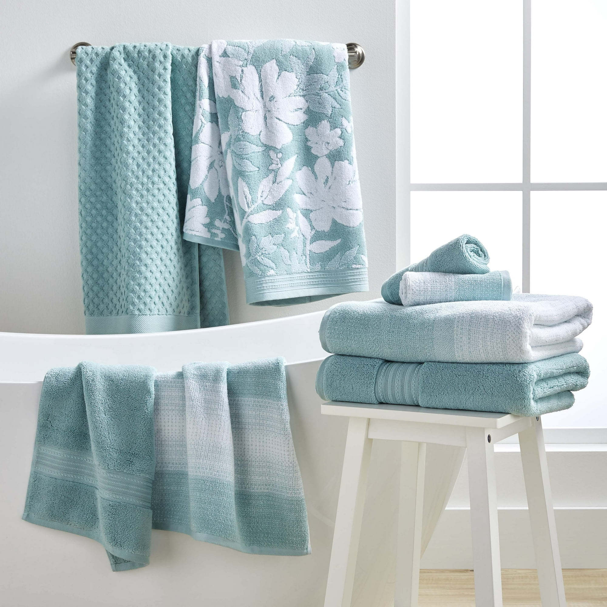 Aquifer towels hanging up by a tub and folded on a white stool