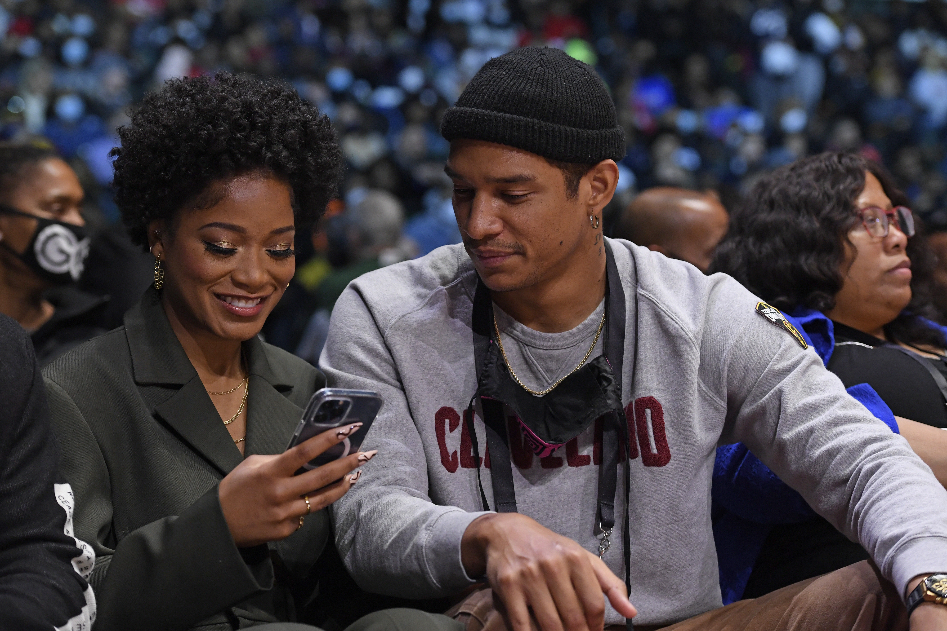 Keke smiling at her phone and Darius peering over as they sit at a game