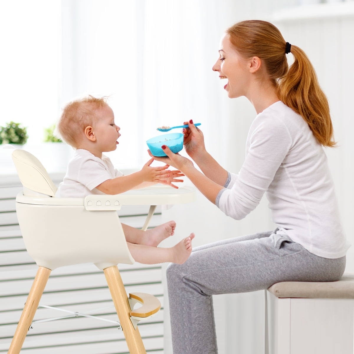 Adult feeds a child in a high chair