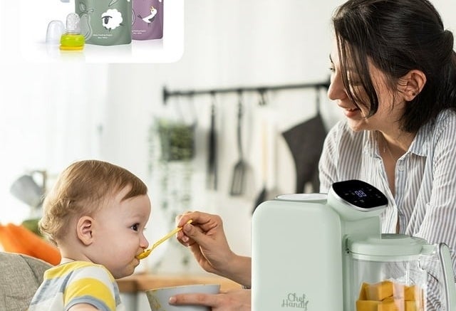 A parent feeds a child while a baby food maker is on a table