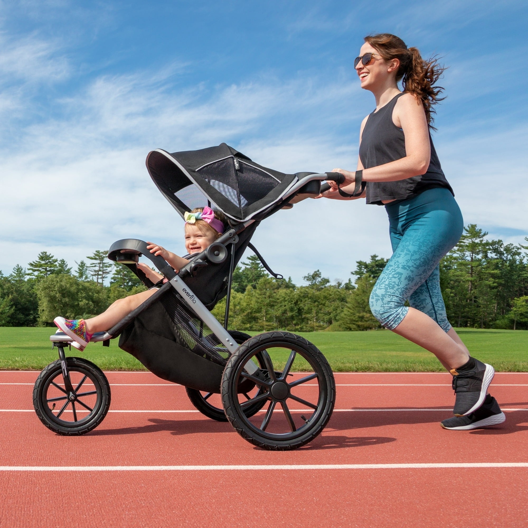 A woman pushes a child in a jogging stroller