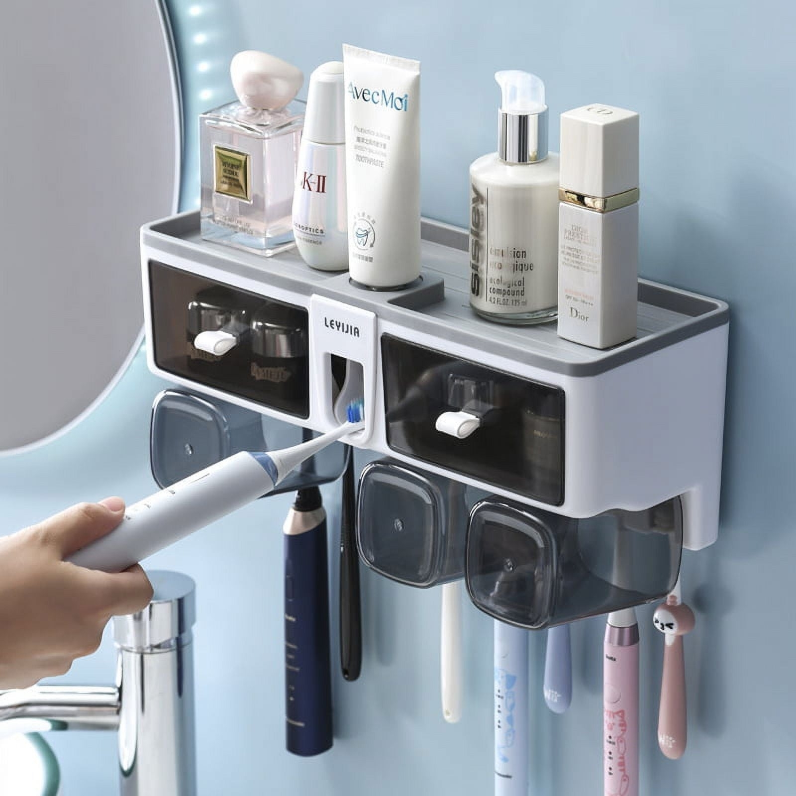 A person placing a toothbrush into the toothpaste dispenser portion of the mounted toothbrush holder