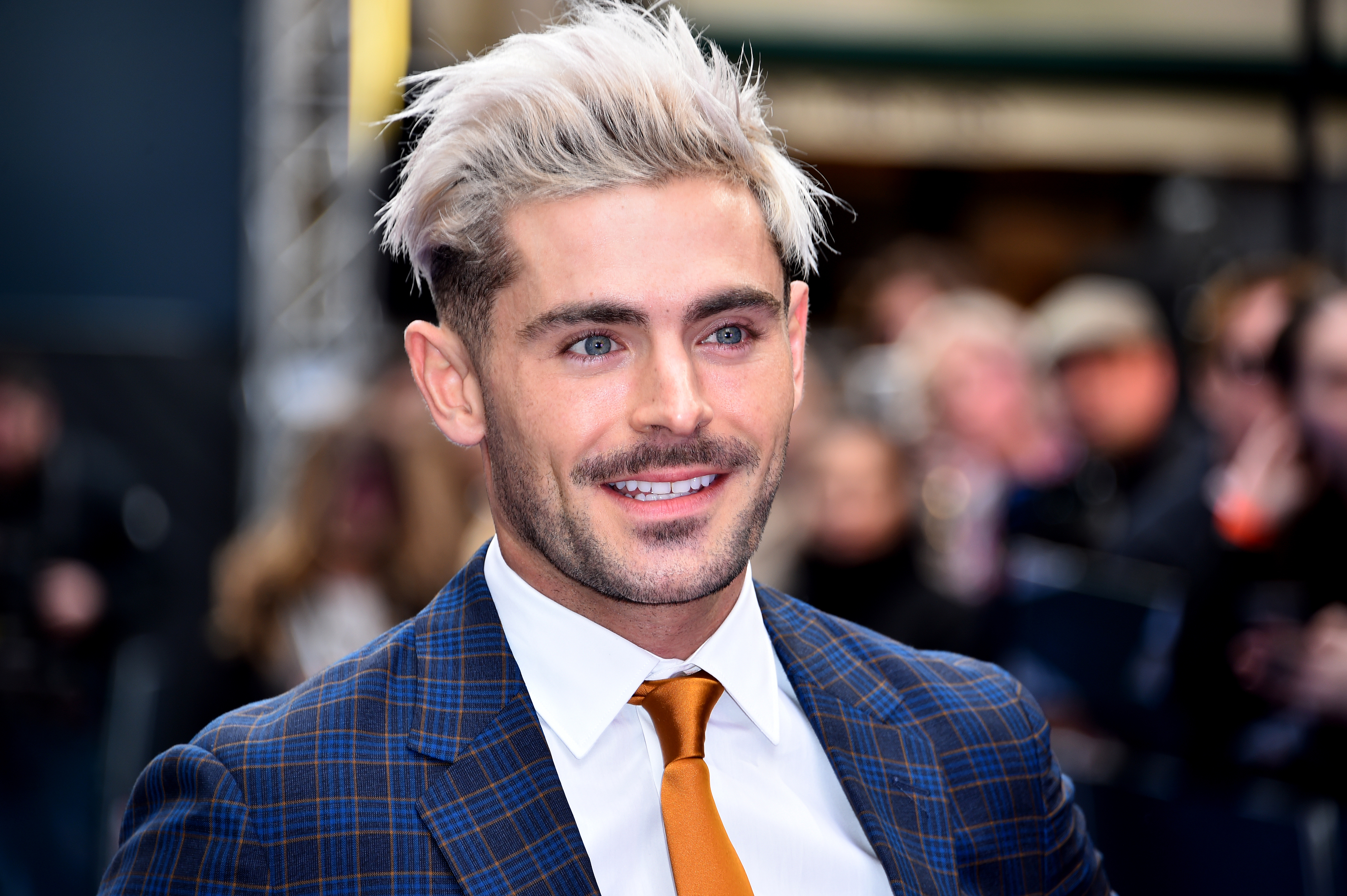 Close-up of Zac smiling and wearing a shirt, jacket, and tie