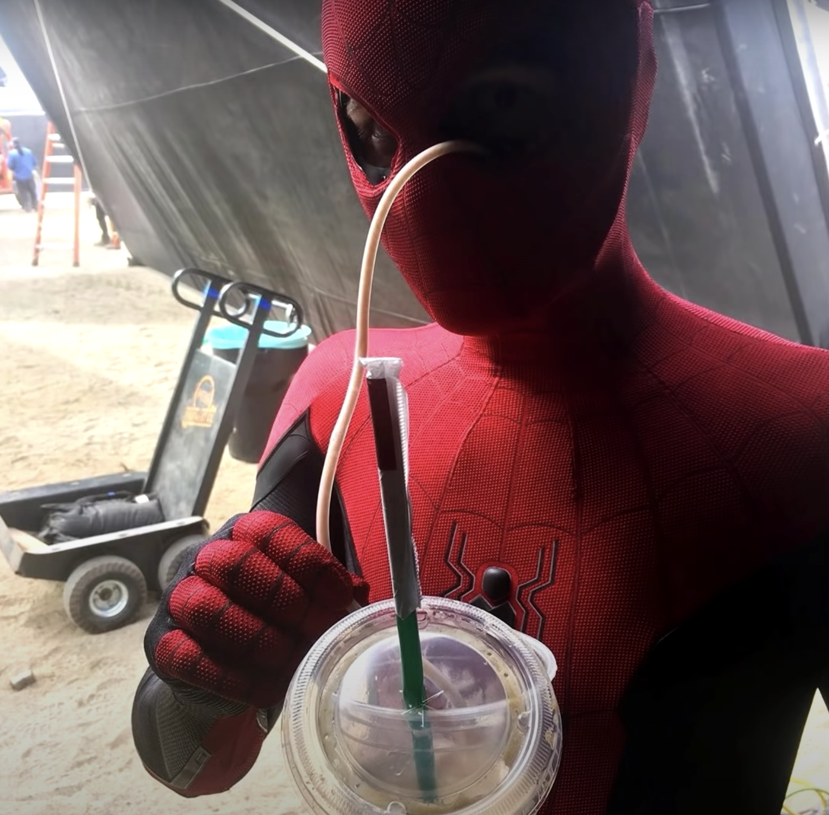 Tom Holland drinking in his Spider-Man suit