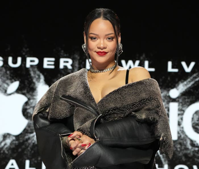 Close-up of Rihanna at a media event in a leather, fur-lined outfit
