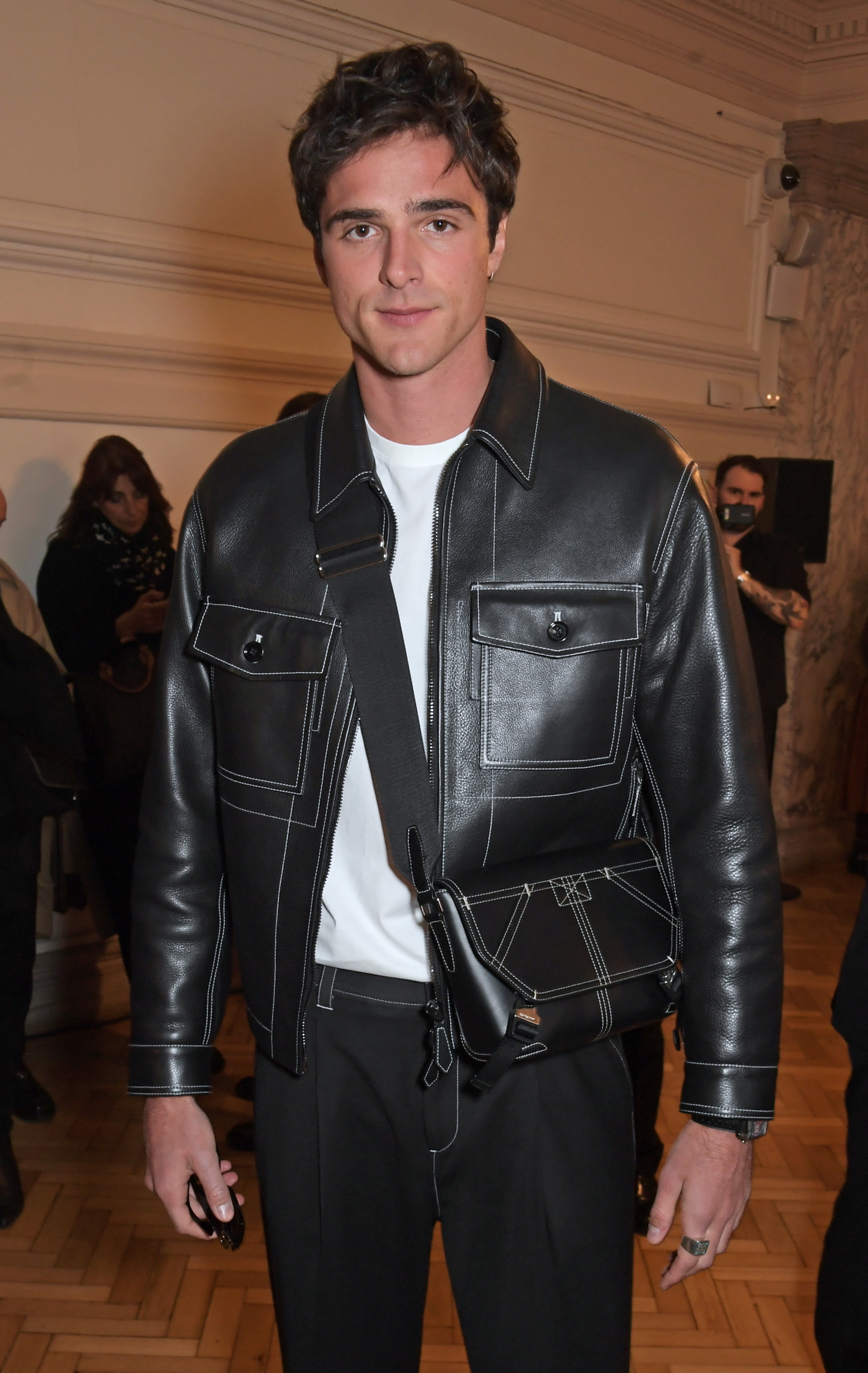 Close-up of Jacob in a leather jacket with a small shoulder bag that reaches his waist