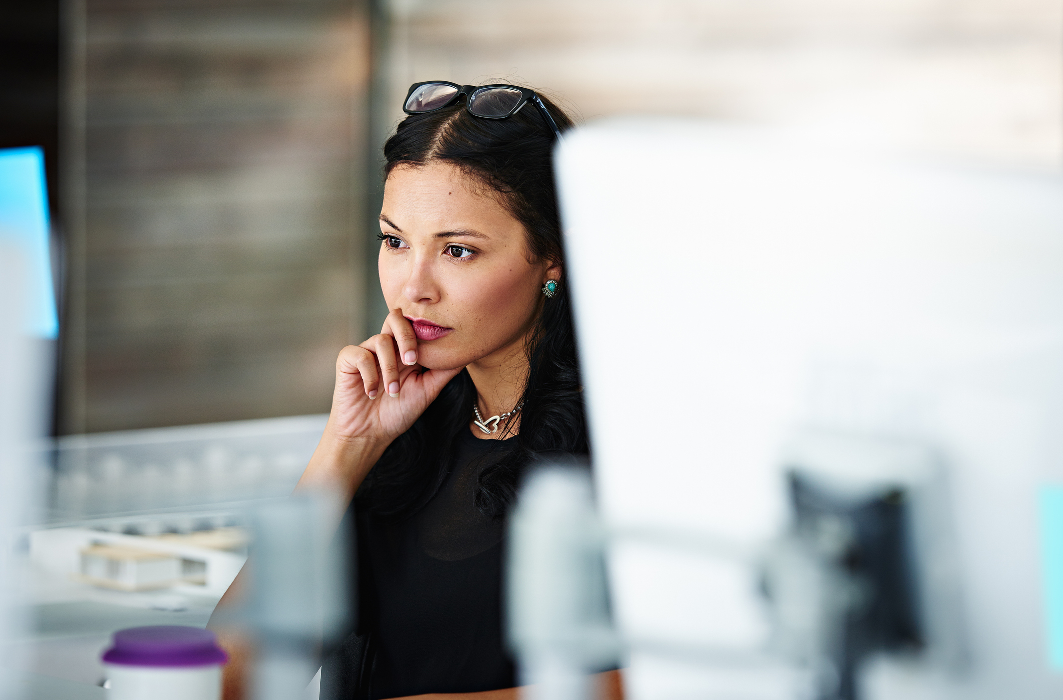A woman looking thoughtful in front of a computer