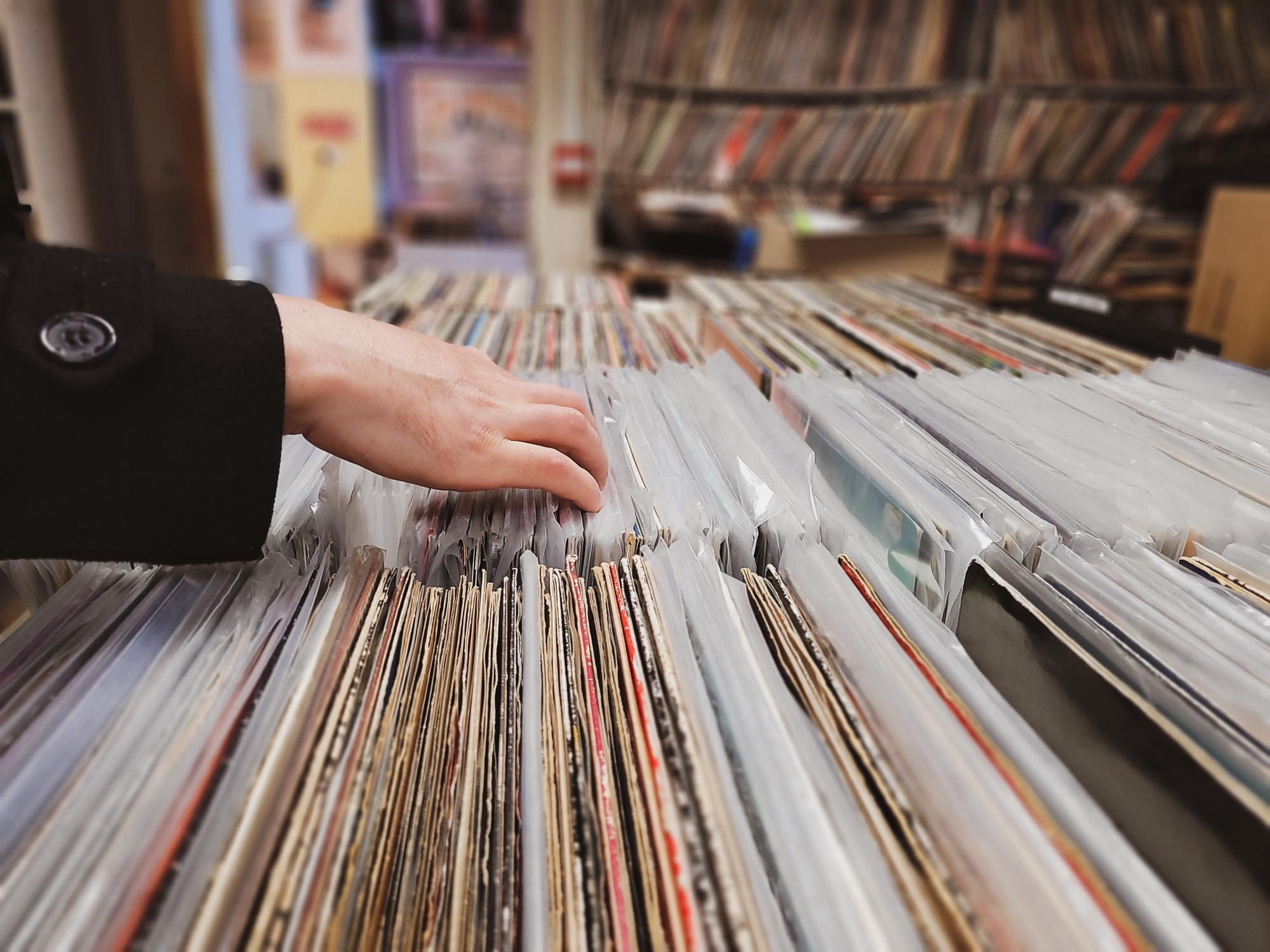 A person rifling through stacks of LPs in a store