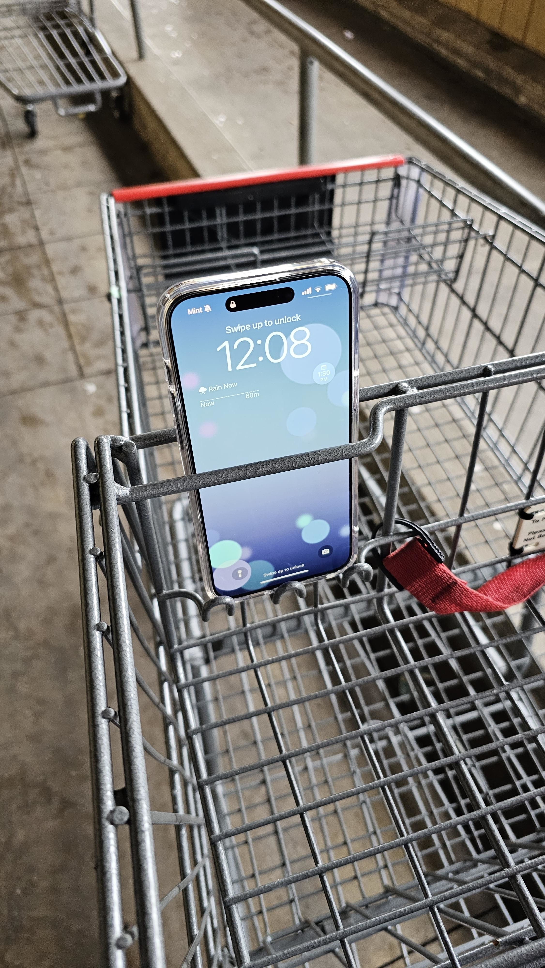 A grocery cart with a small slot at the top and front with a cellphone in it