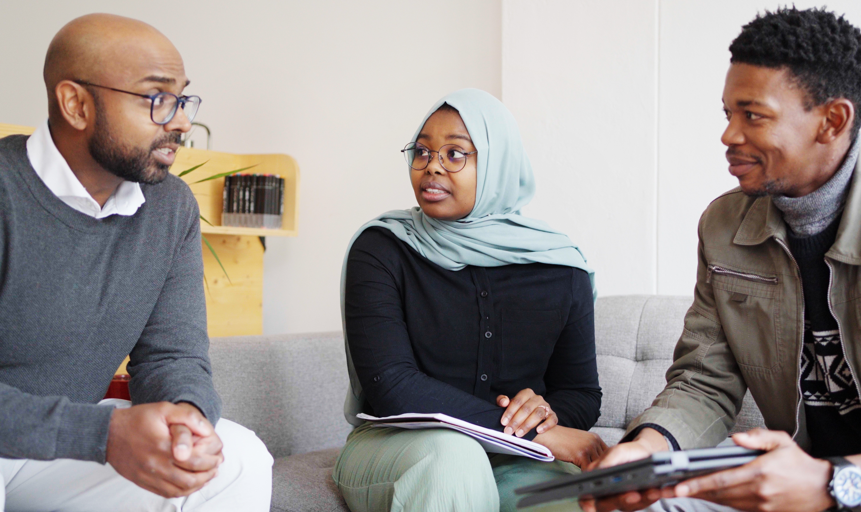 a black muslim woman sitting between two men