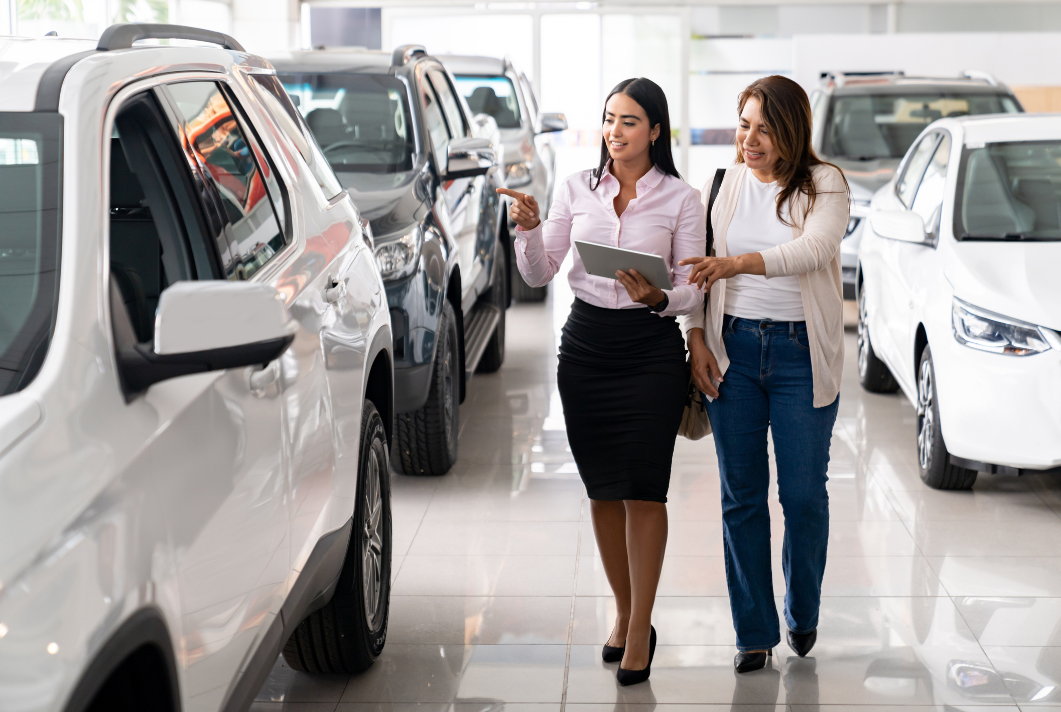 a female cars salesperson showing a female customer a car