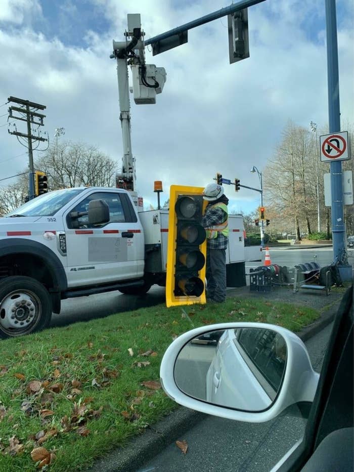 A construction worker holding a traffic light that's as tall as he is