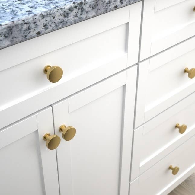 gold-tone cabinet knobs on white kitchen cabinets