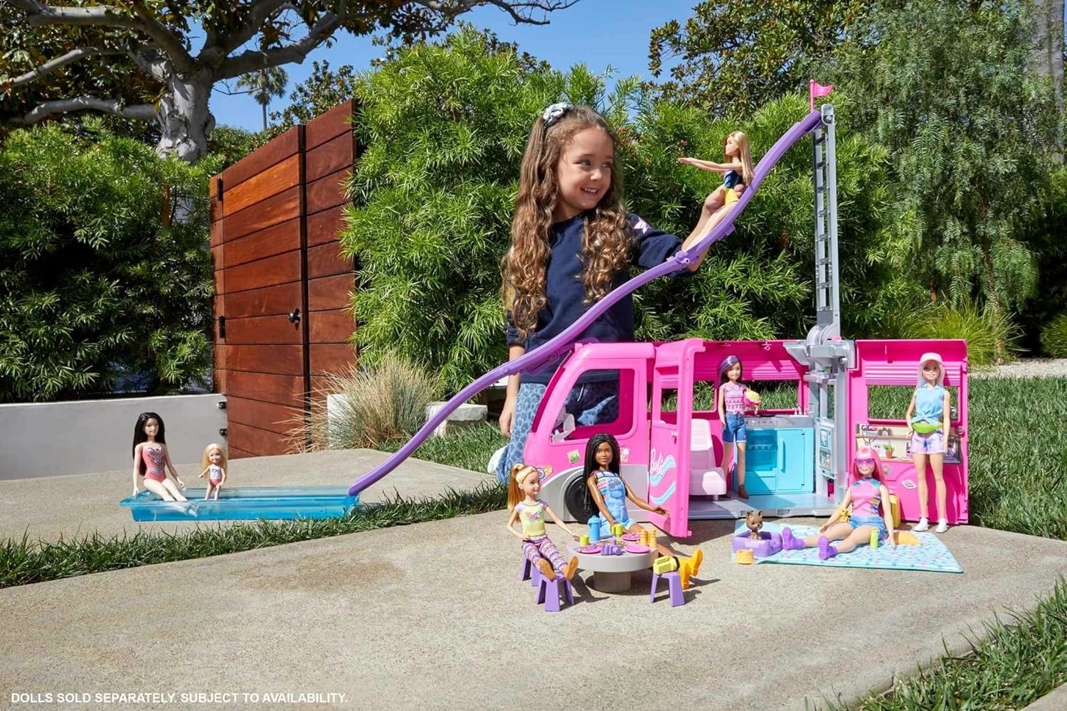 a child playing with the barbie camper van and several dolls