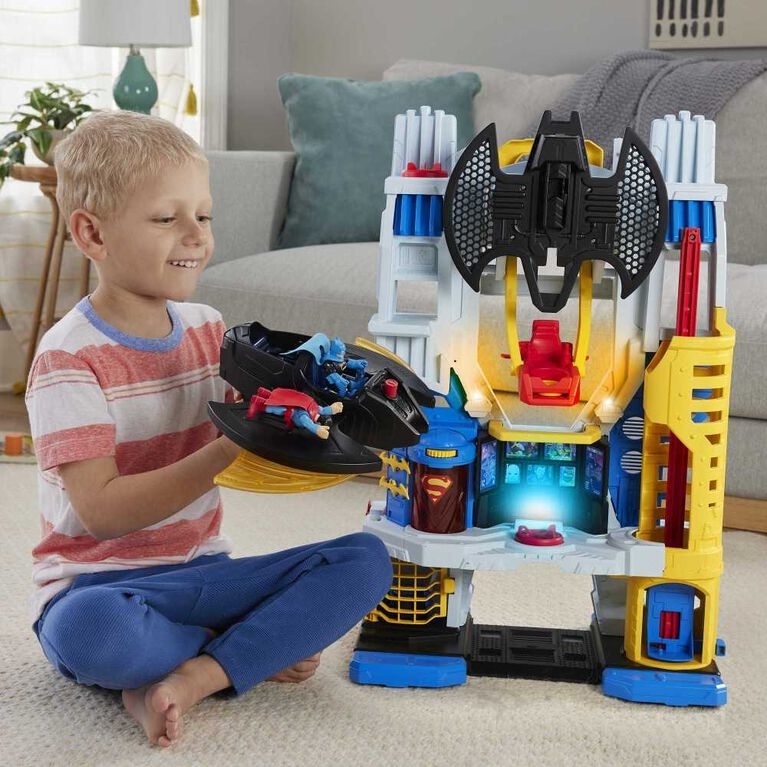 a child happily plays with the dc super friends headquarters in their living room