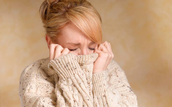 woman pulling her sweater to cover her face