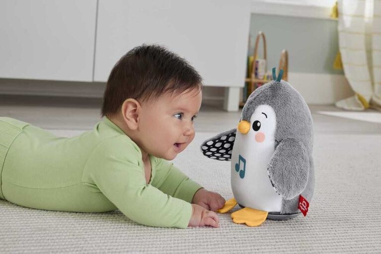 a baby playing with the flapping penguin toy