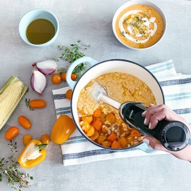 black immersion blender in pot filled with vegetable soup