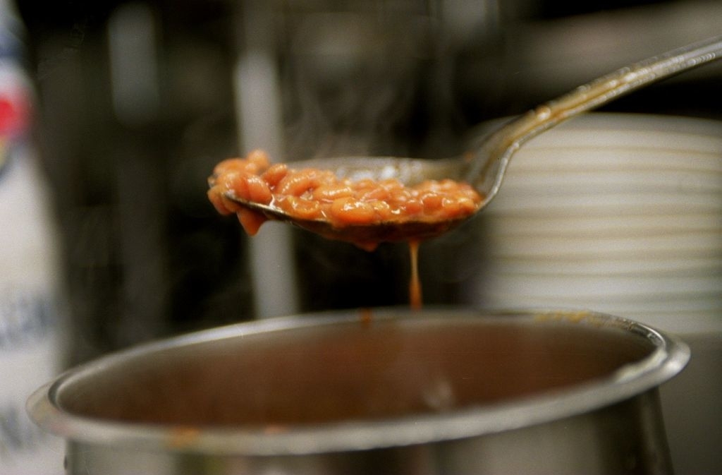 baked beans being spooned out of a pot