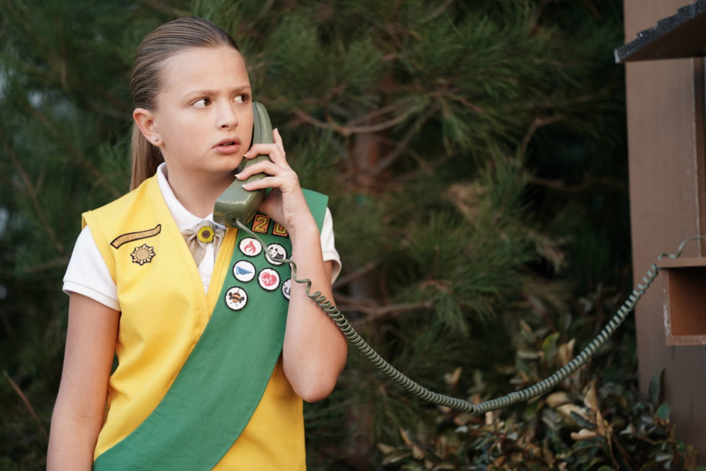 her in a girl scouts uniform using a phone