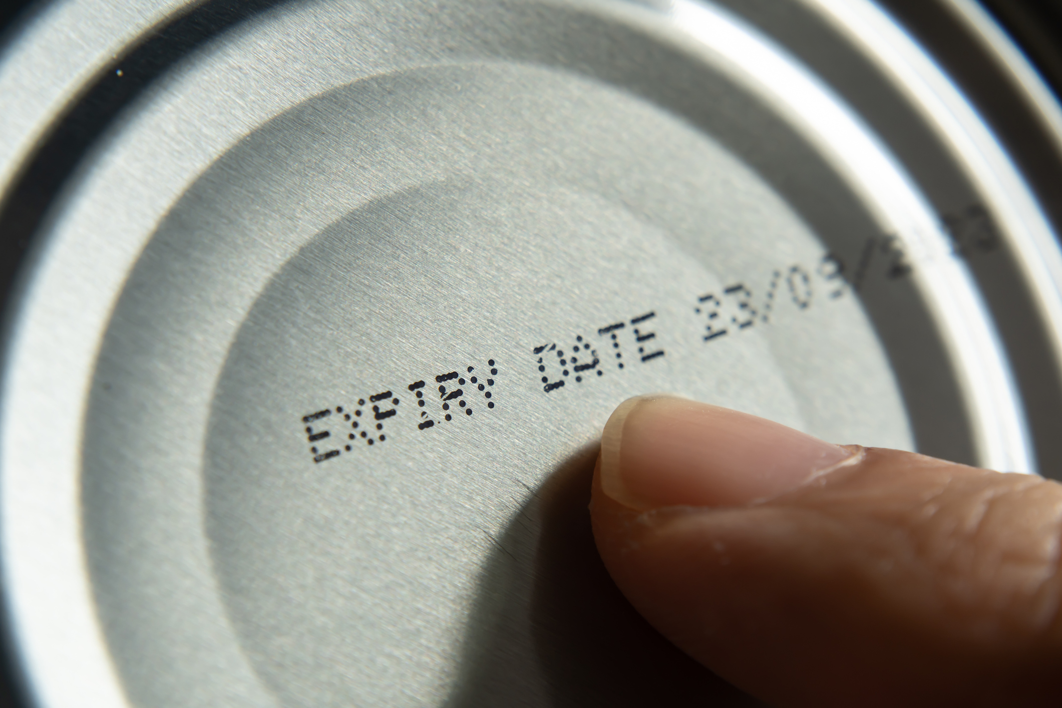 someone pointing at an expiration date on a can