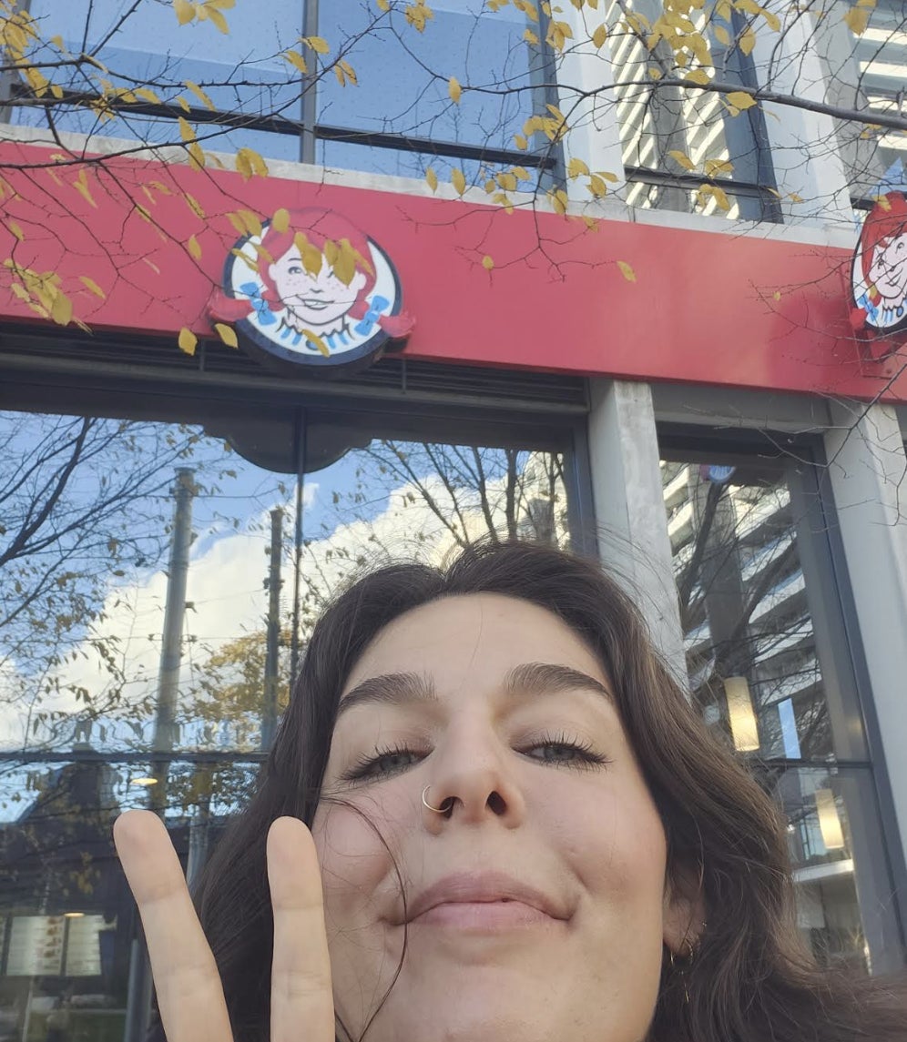 brittany giving the piece sign with her fingers in front of a wendys restaurant