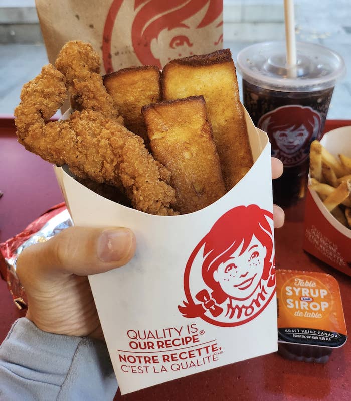 Brittany holding a large fry container filled with chicken strips and french toast